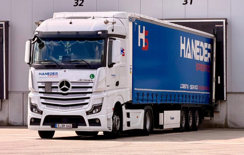 HANEDER Sattelzug mit blauem Planenauflieger an der Verladerampe